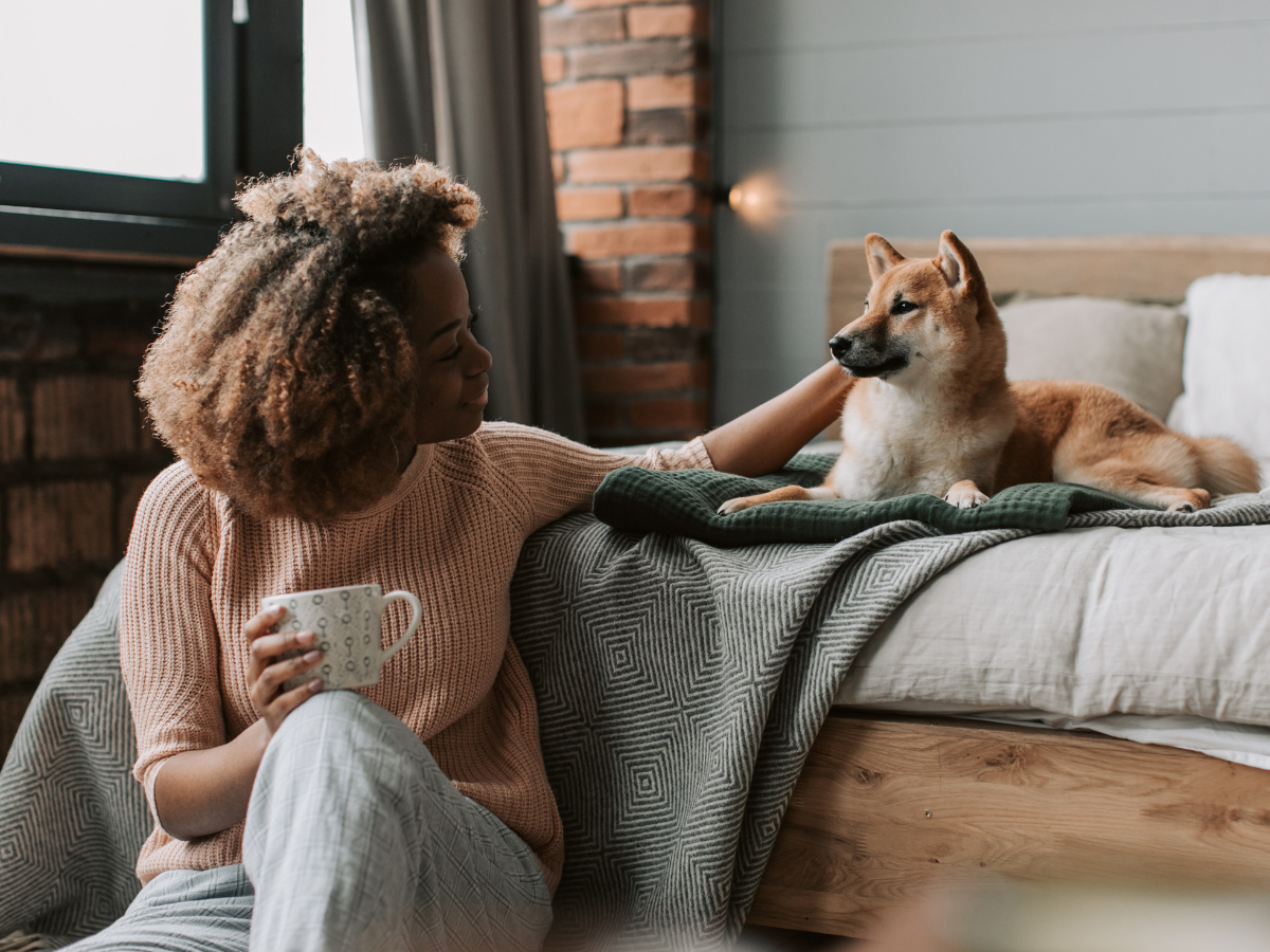 Woman with a mug and a Shiba Inu on the bed
