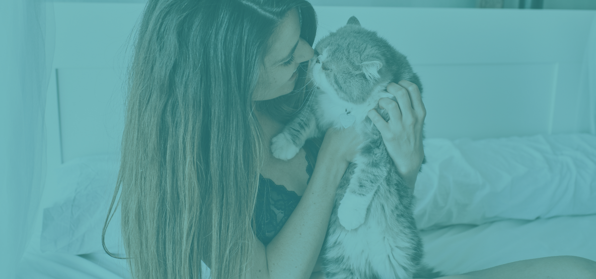 Woman holding a cat in a bedroom setting